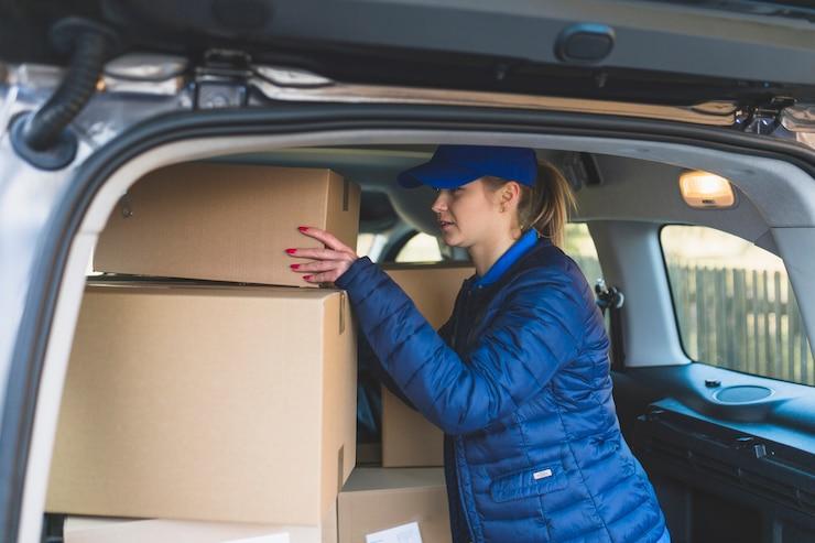 mujer repartidora de Mercado Libre cargando cajas en su auto
